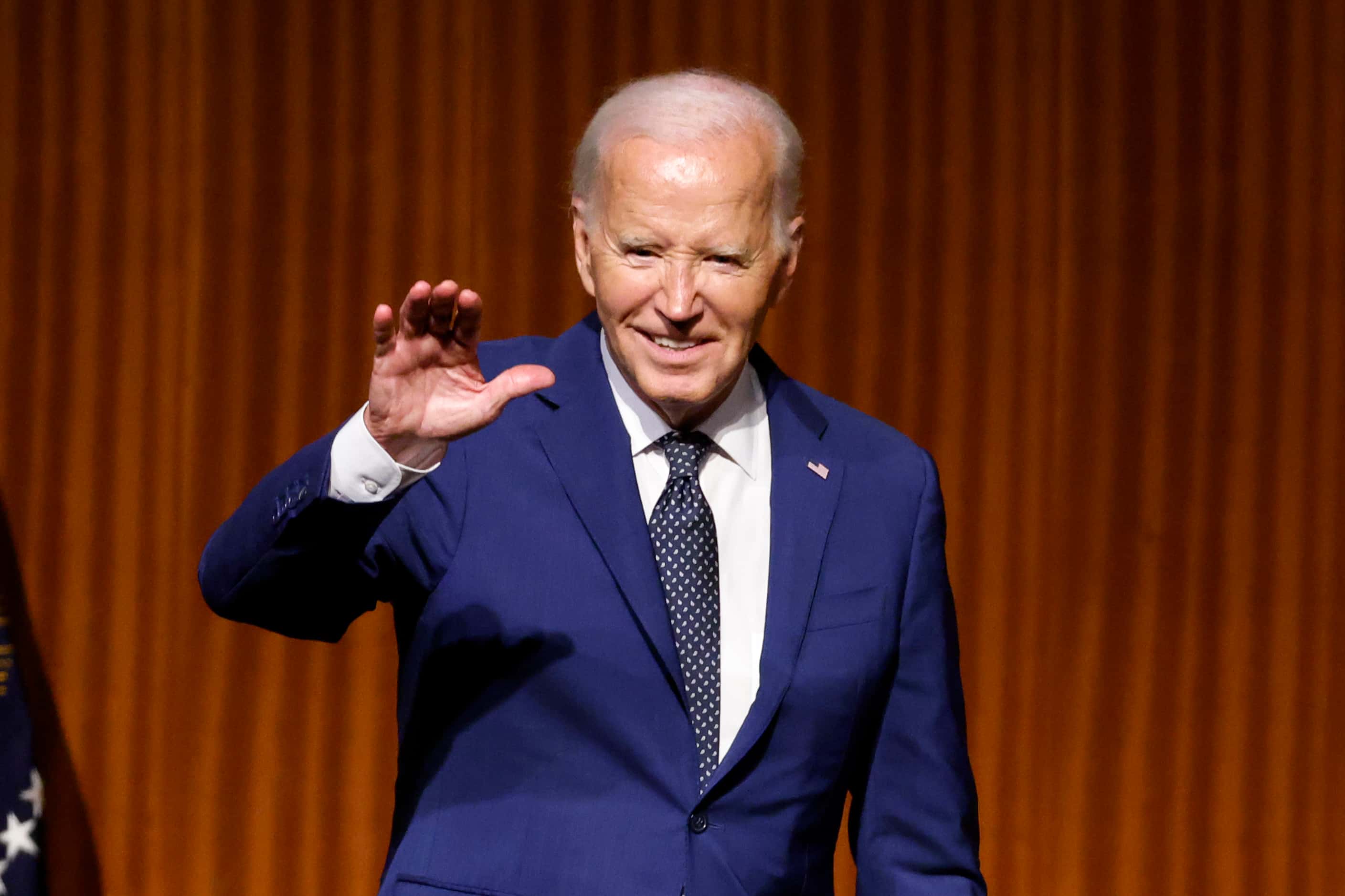 President Joe Biden waves to the audience after speaking during an event commemorating the...