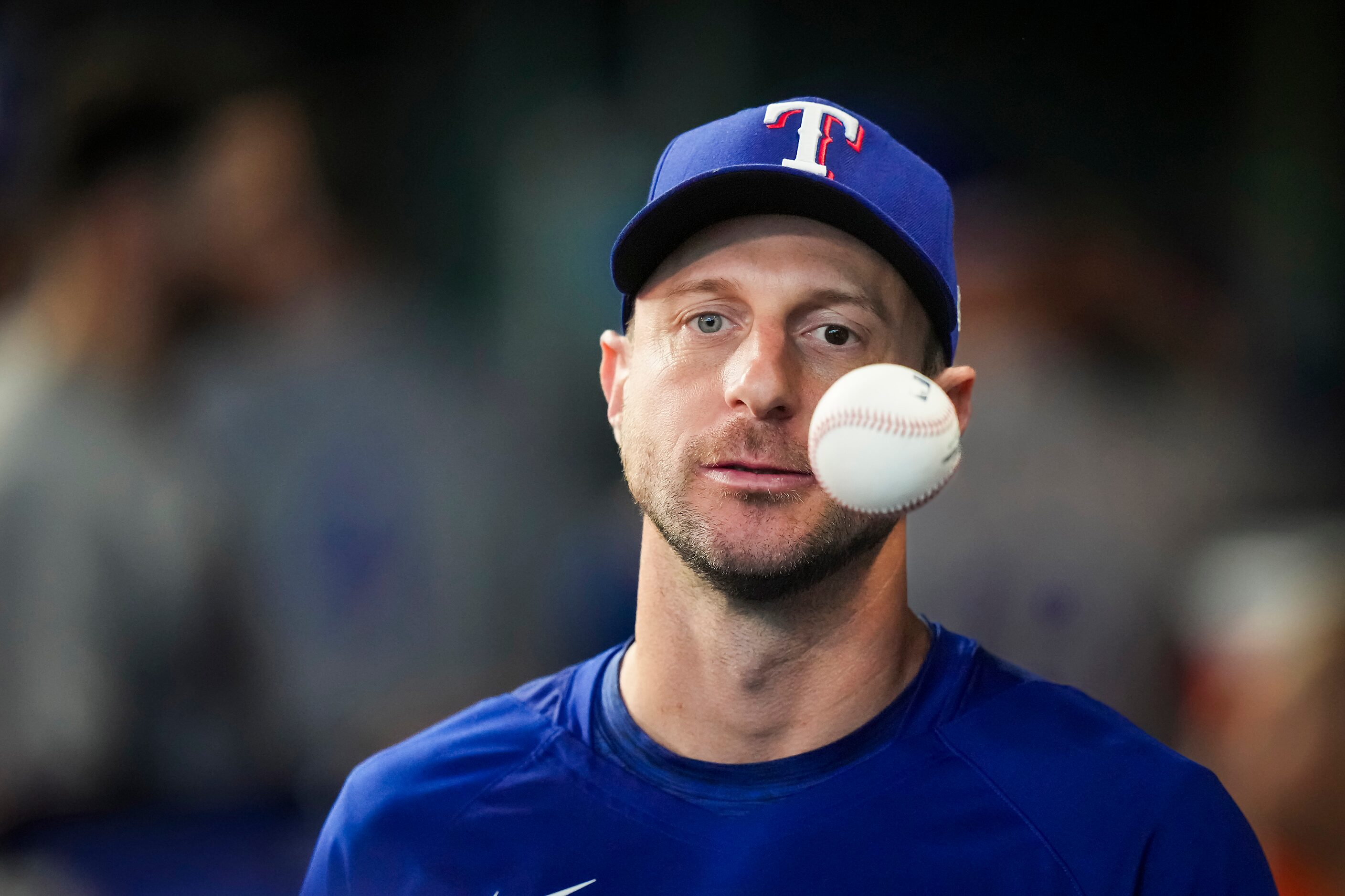 Texas Rangers pitcher Max Scherzer tosses a ball in the dugout during the third inning in...