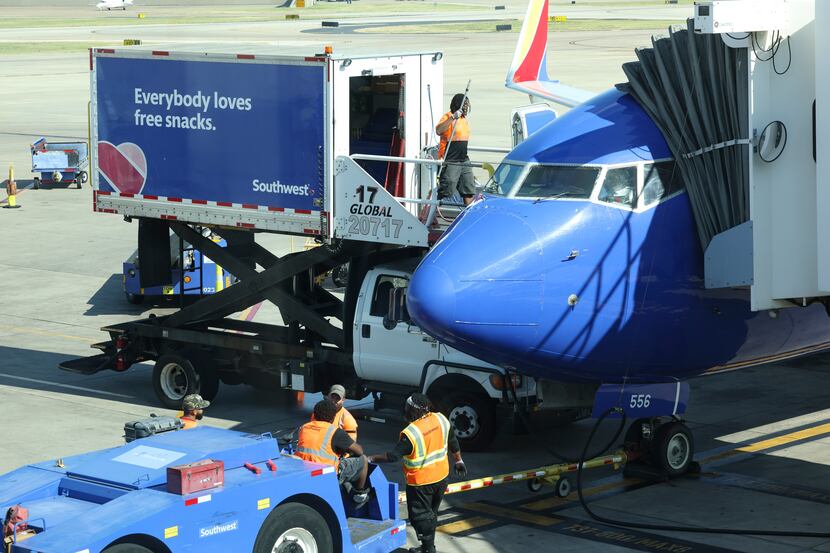 Airport workers wait on the tarmac as people board a plane to Washington, D.C., on July 1 at...