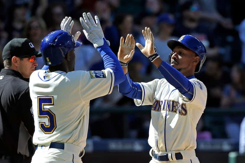 Seattle Mariners' Guillermo Heredia (5) and Jarrod Dyson share congratulations after they...