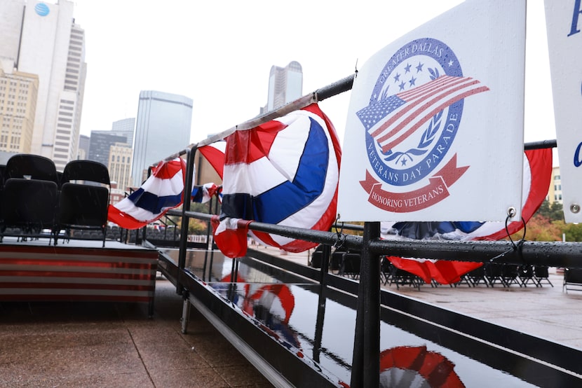 Rain drips off of chairs, ramps, patriotic bunting. flags and posters where the Veterans Day...