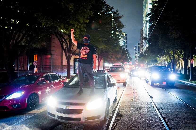 A demonstrator stands atop a car as protesters block the intersection of  McKinney at Pearl...