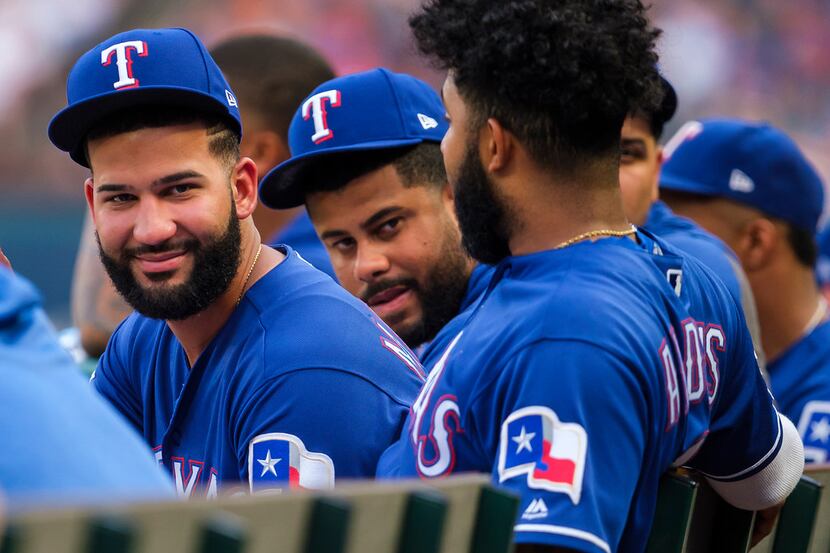 Texas Rangers outfielder Nomar Mazara (left) watches from the dugout with shortstop Elvis...