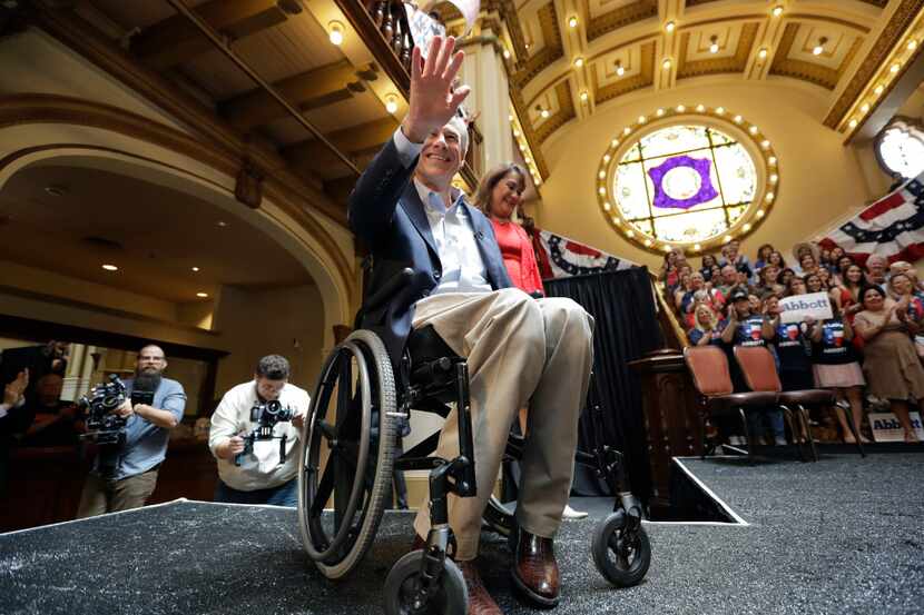 Texas Gov. Greg Abbott waves to supporters as he and his wife, Cecilia, arrive for an event...