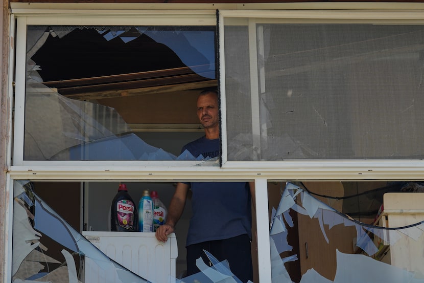 A man looks at a damaged window of a house following an attack from Lebanon, in Acre, north...