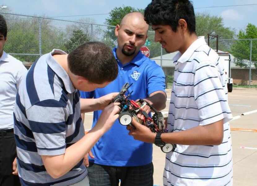 
 Instructor Jose Guerrero, center, helps team members Bullis and Carlos Lopez repair one of...