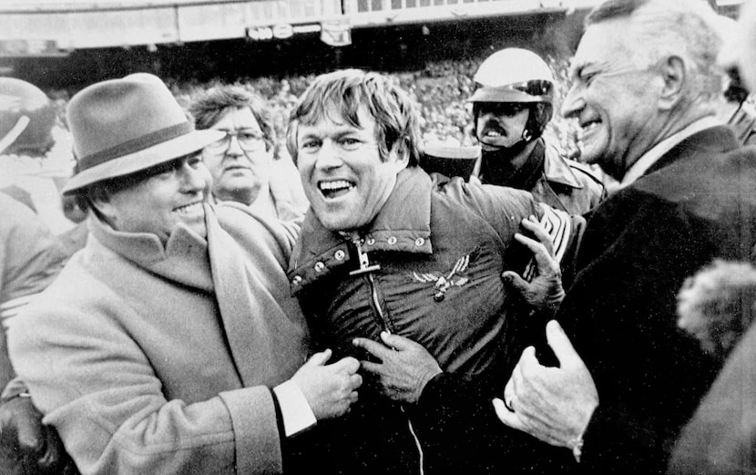 Eagles owner Leonard Tose, right, and general manager Jim Murray hug coach Dick Vermeil...