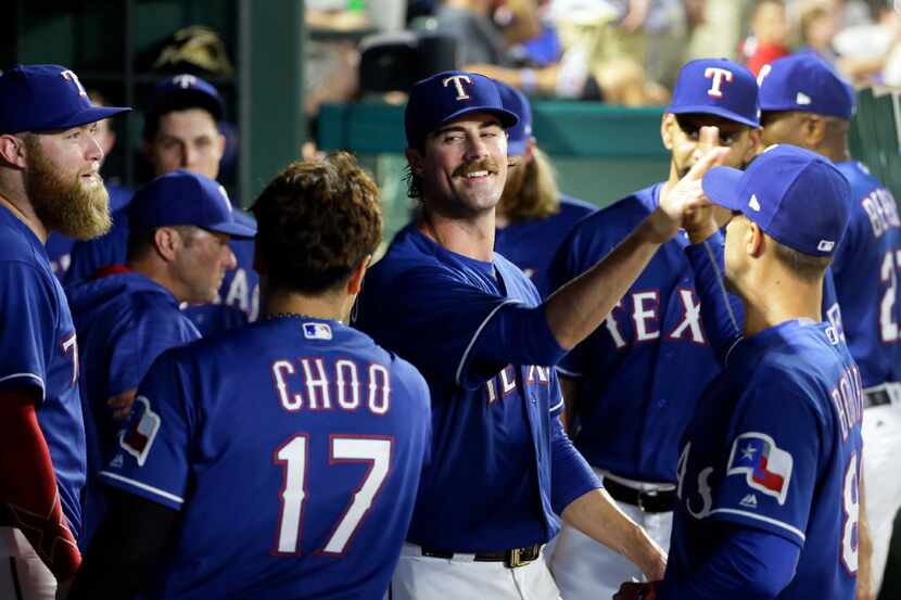 Texas Rangers' Andrew Cashner, left, Shin-Soo Choo (17), of South Korea, and staff member...