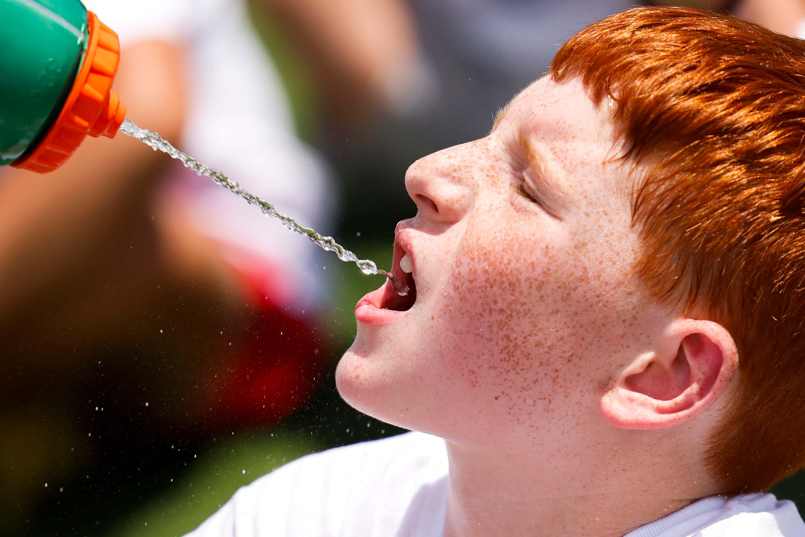 Matthew Klaassen, 9, gets a sip of water while waiting on a line to practice and interact...
