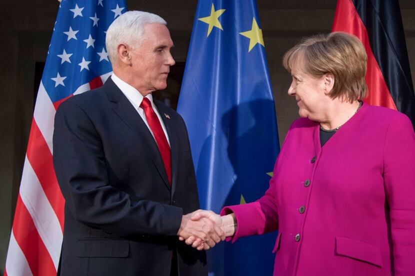 German Chancellor Angela Merkel (R) and US Vice President Mike Pence shake hands at a photo...