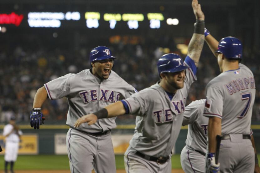 Texas RF Nelson Cruz is congratulated by teammates Mike Napoli and David Murphy as they...