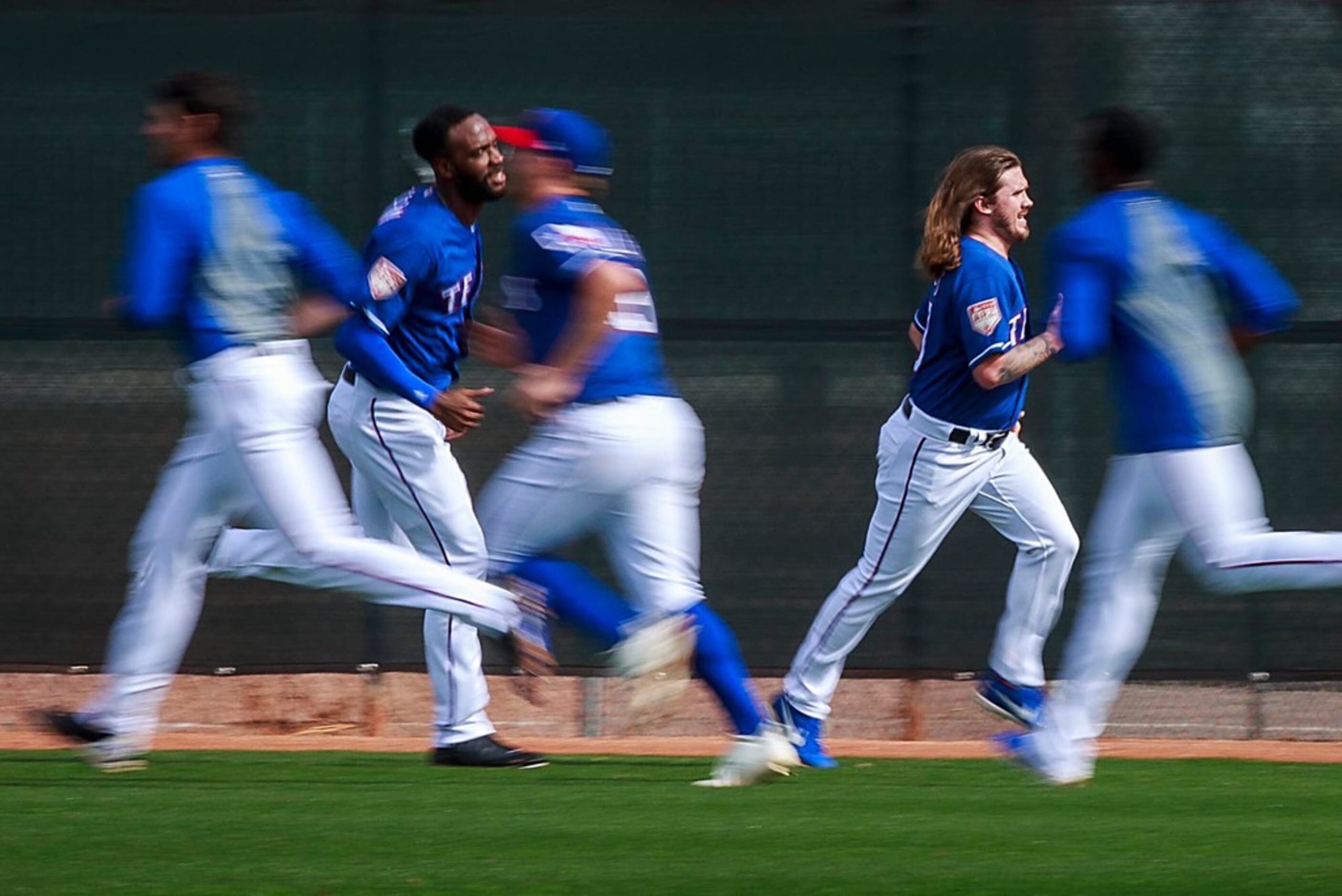 Texas Rangers pitchers Zac Curtis (right) and Taylor Hearn (left) run in the outffield with...