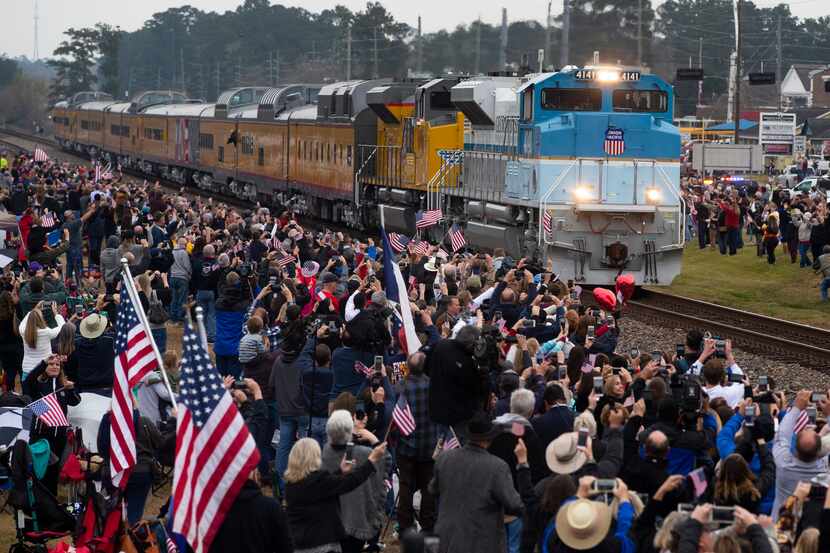 Mourners watch as a train carrying the remains of former President George H.W. Bush in...