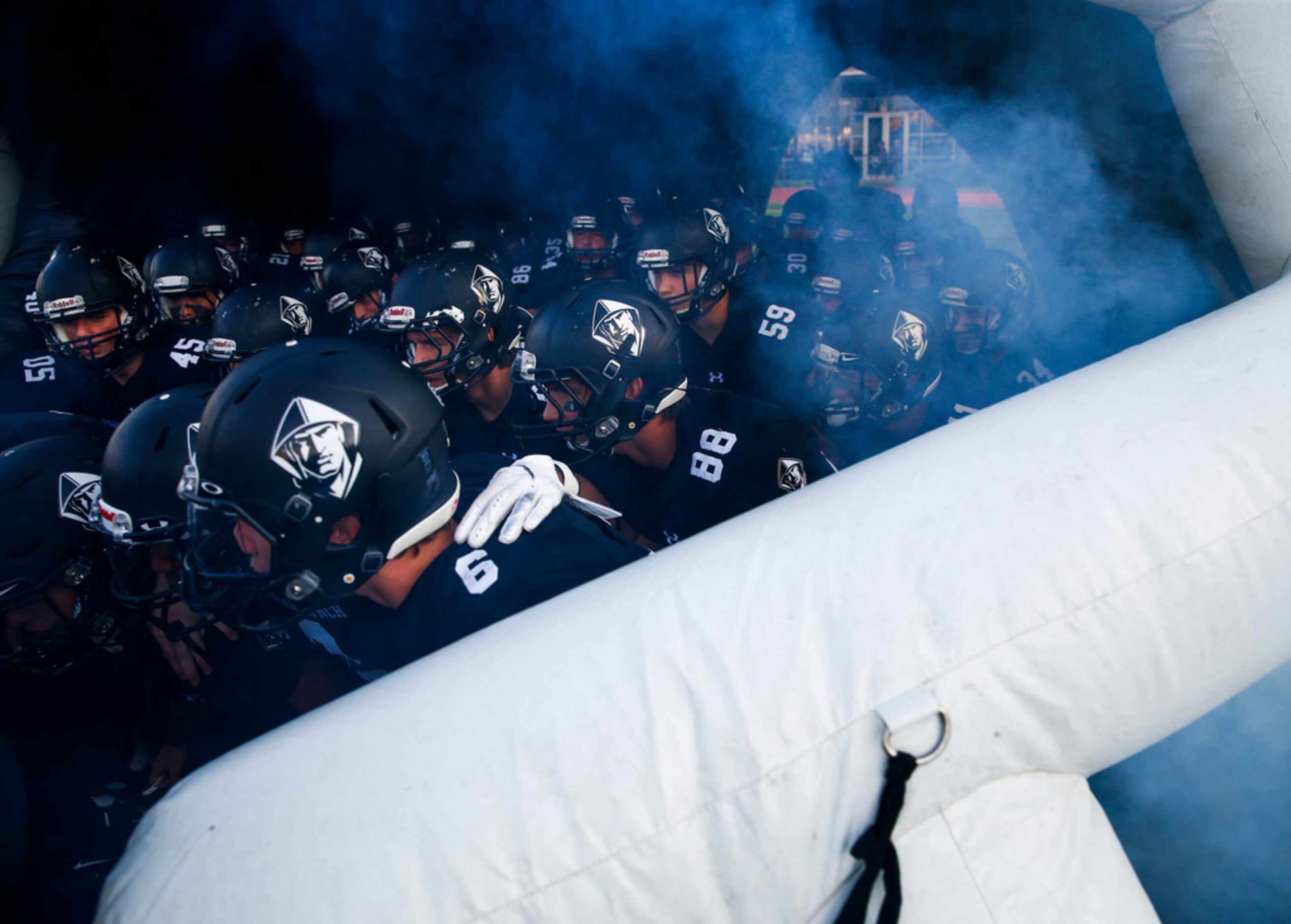 The Bishop Lynch Friars break onto the field prior to a high school football game between...