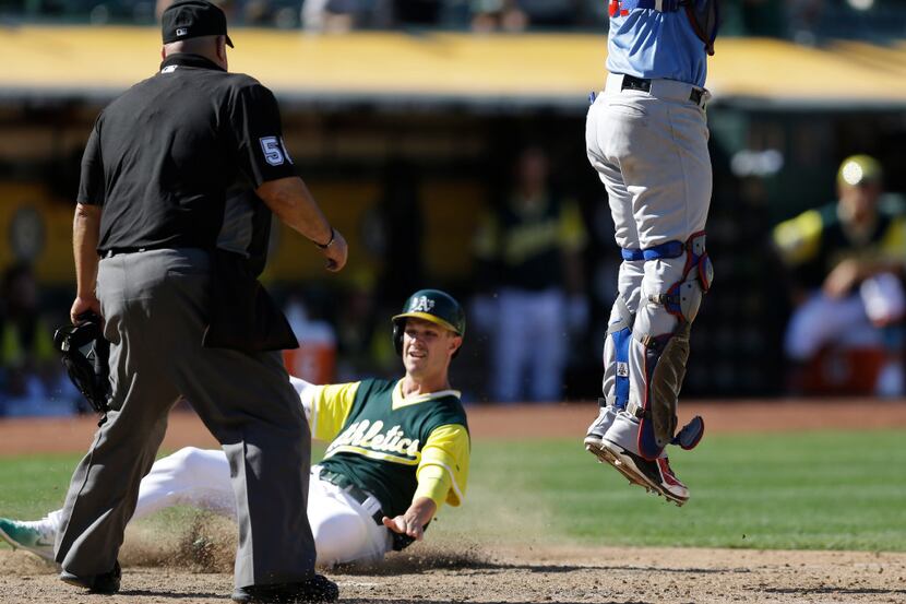 Oakland Athletics' Boog Powell, center, slides to score beneath Texas Rangers catcher...