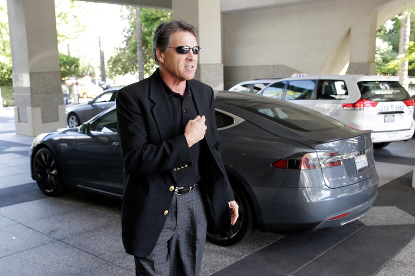 Texas Gov. Rick Perry prepares to talk to reporters Tuesday after driving up in a Tesla...