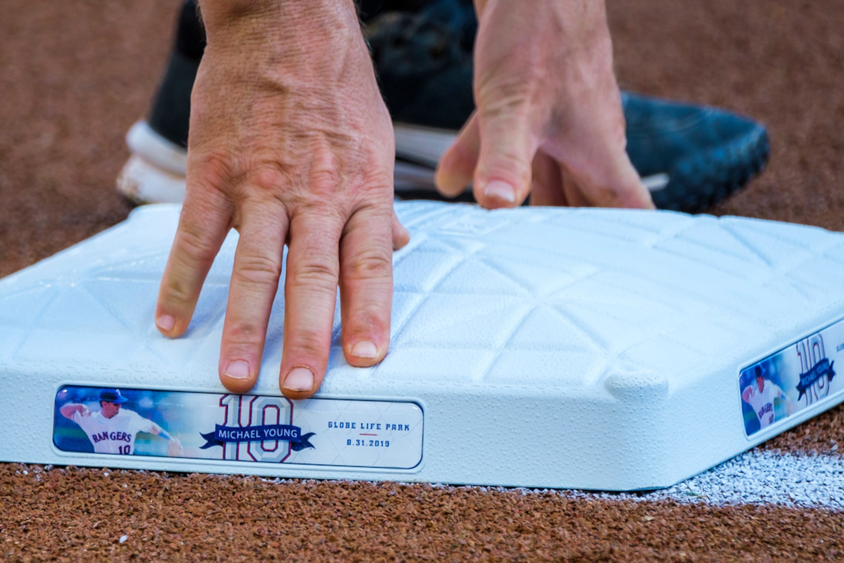 A groundskeeper positions third base bearing Michael YoungÃs number before ceremonies to...