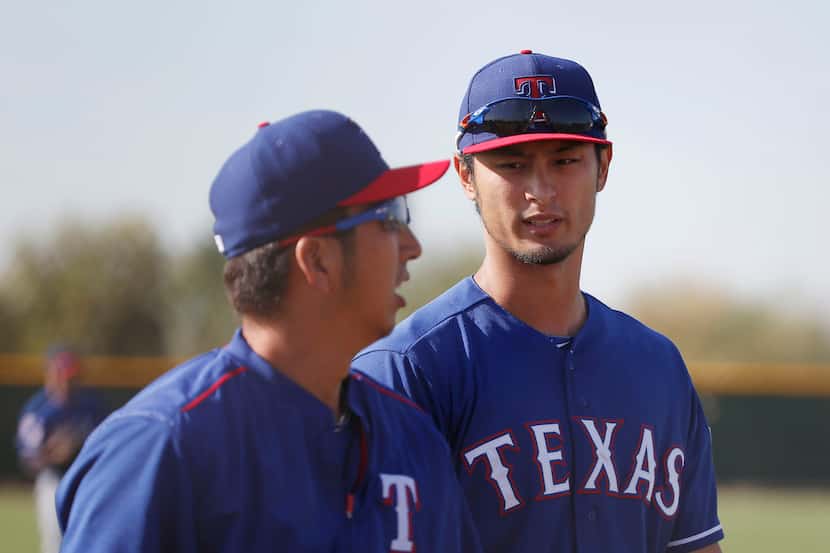 Texas Rangers pitchers Kyuji Fujikawa and Yu Darvish speak after warming up their arms...