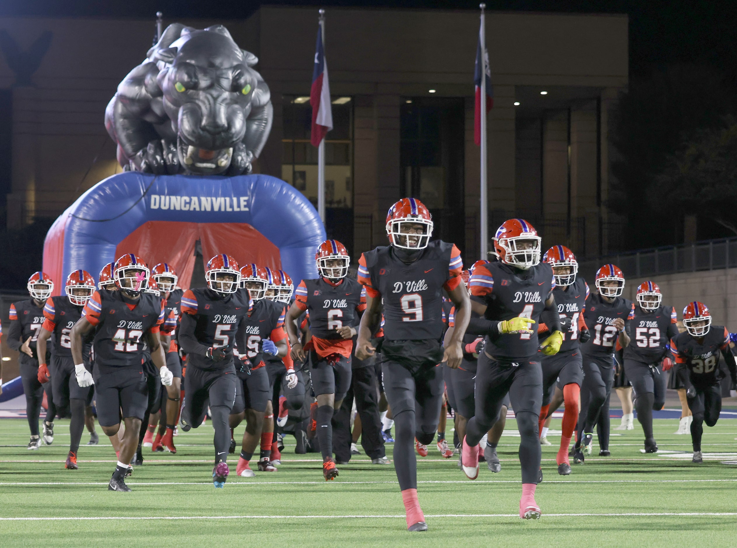 Duncanville players race onto the field from their team inflatable prior to the opening...