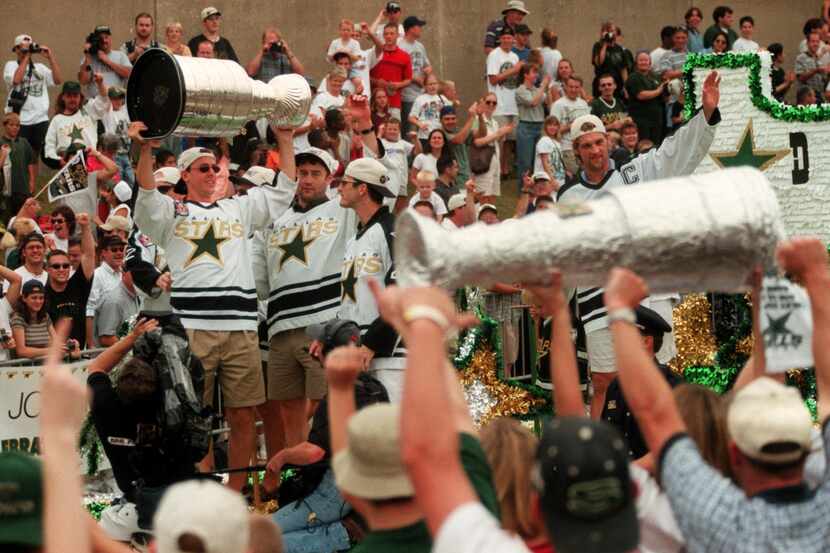 Stars player Joe Nieuwendyk holds the Stanley Cup next to teammates Ed Belfour and Guy...