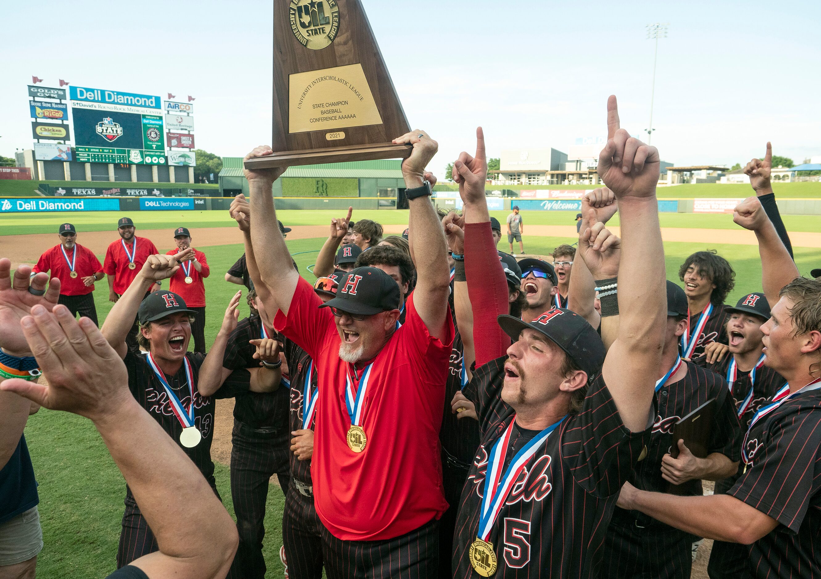 Rockwall-Heath head coach, Greg Harvey and the team celebrate with the championship trophy...