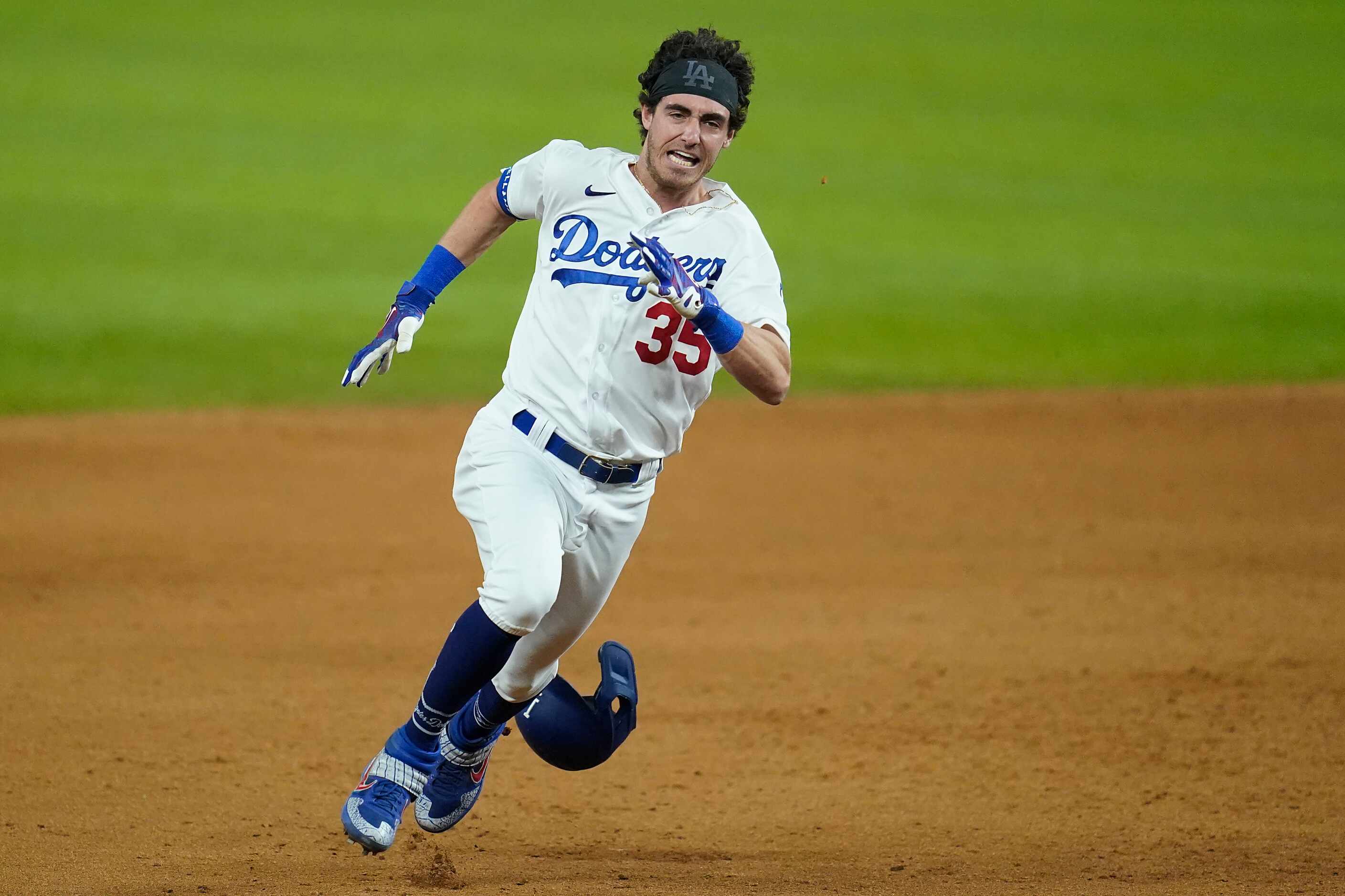 Los Angeles Dodgers center fielder Cody Bellinger digs for third base on an RBI triple...