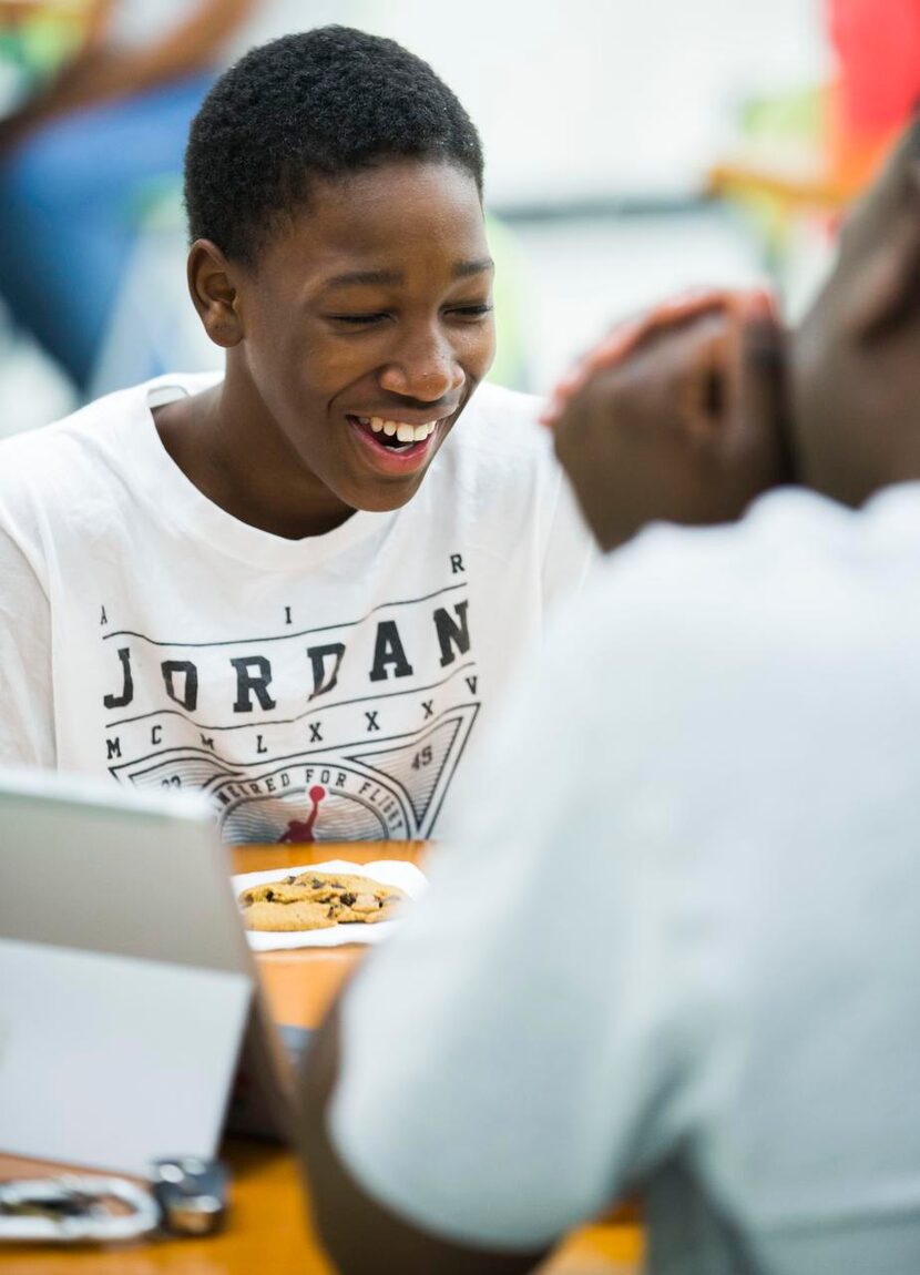 
Jody Legans Jr., 14, laughs with his father, Jody Legans, during a community barecue for...