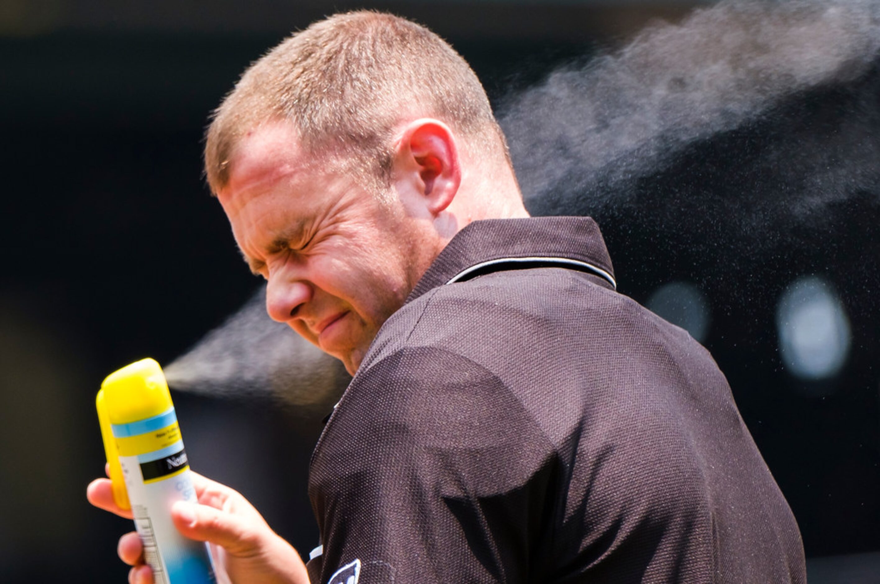 Umpire Will Little applies sunscreen during the first inning of a game between the Texas...