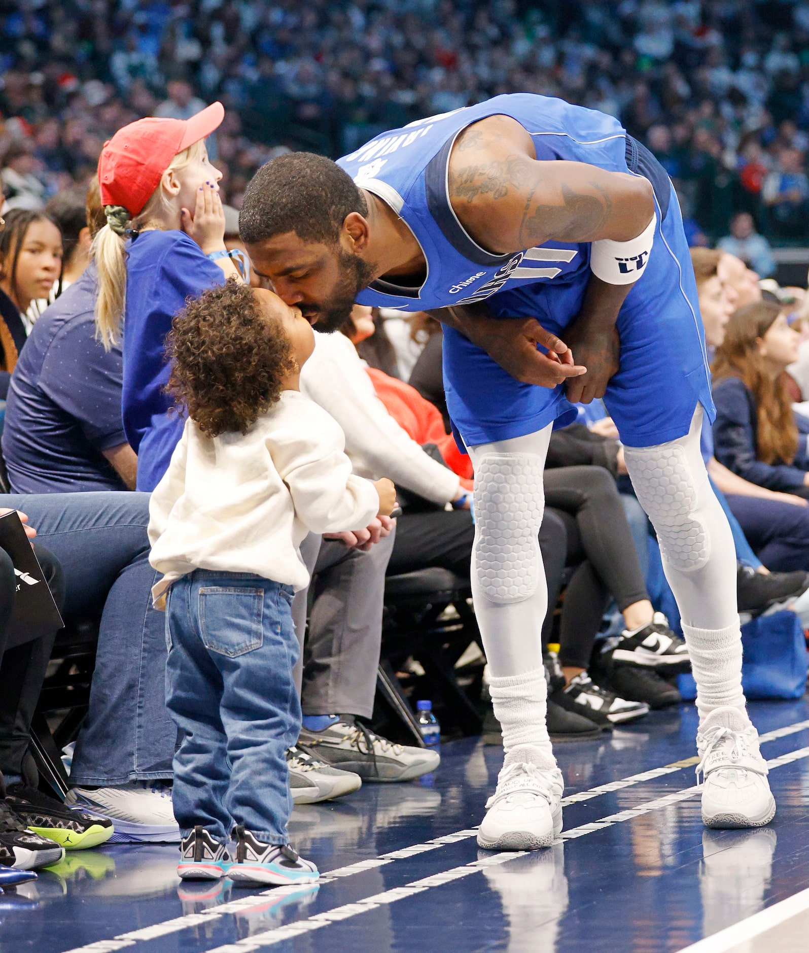 Dallas Mavericks guard Kyrie Irving (11) kisses his child during a timeout in the first half...