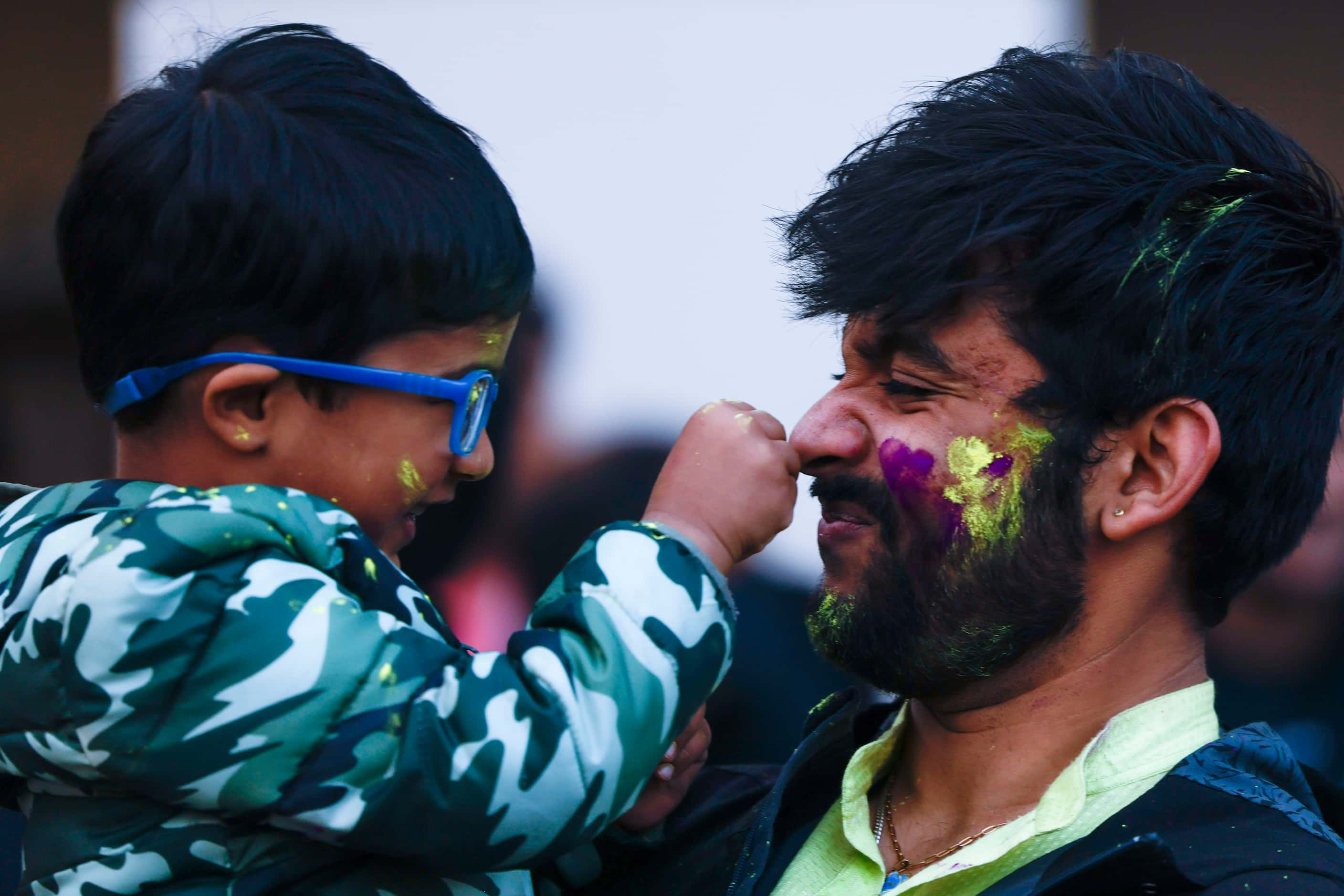 Ayaan Agarwal, 4, (left), applies color on Abhishek Amol Mishra during Holika Dahan, a part...