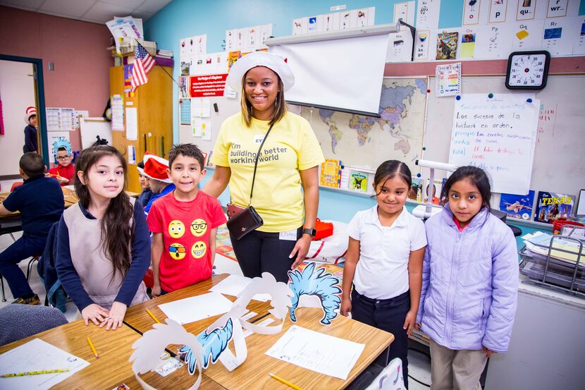 An EY volunteer stands with four young local students for a United Way Reading Day activity.