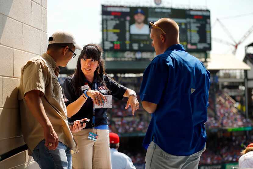 Texas Rangers usher and HKS architectural designer Margarita Aguirre helps fans Leland Tieh...