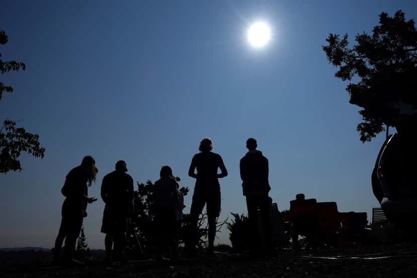 FILE - People gather near Redmond, Ore., to view the sun as it nears a total eclipse by the...