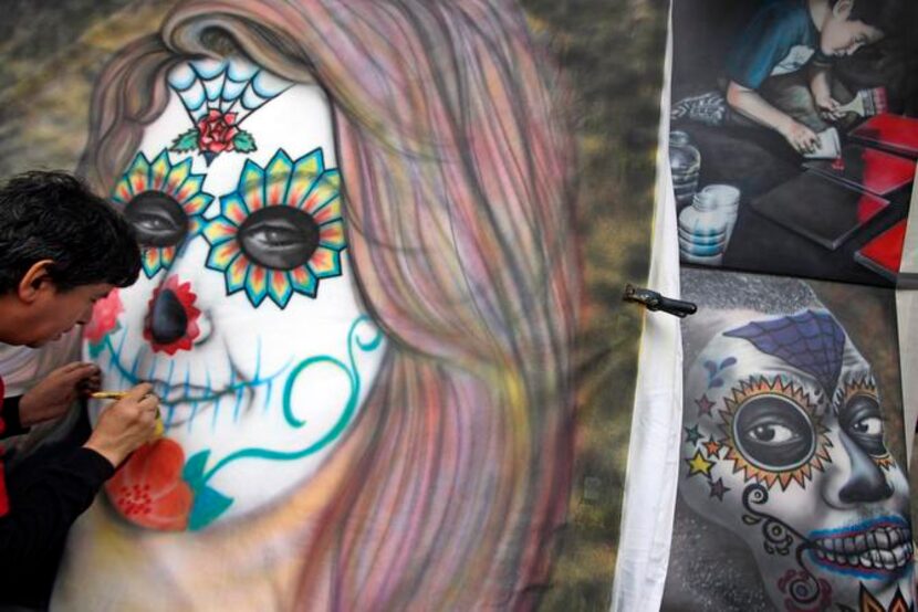 
Eddie Walker of Dallas worked on a portrait of a woman wearing Day of the Dead-style face...