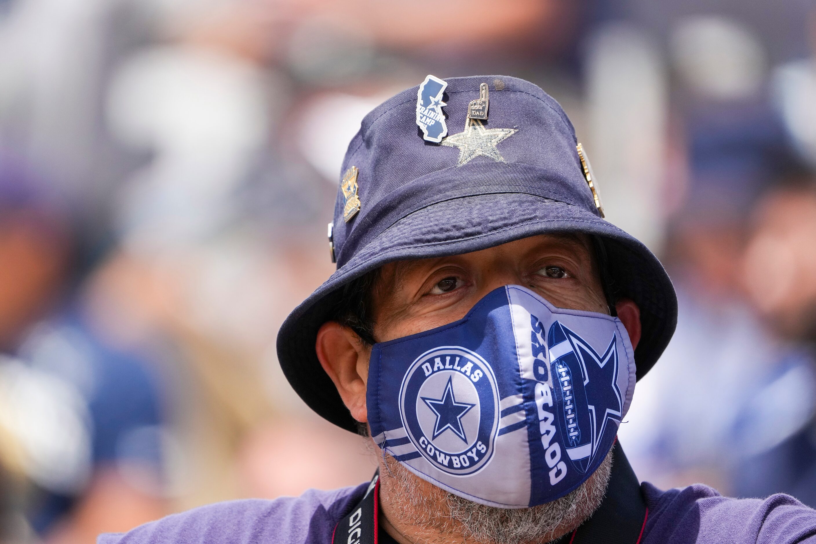 A fan wears a Dallas Cowboys face mask as he watches from the stands during a practice at...