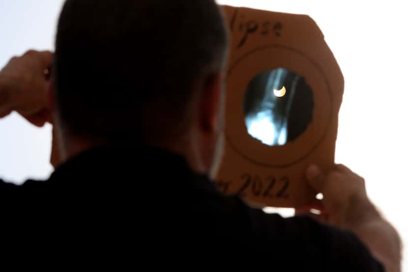 Un hombre utiliza un artefacto hecho a mano para protegerse y poder ver el eclipse parcial...