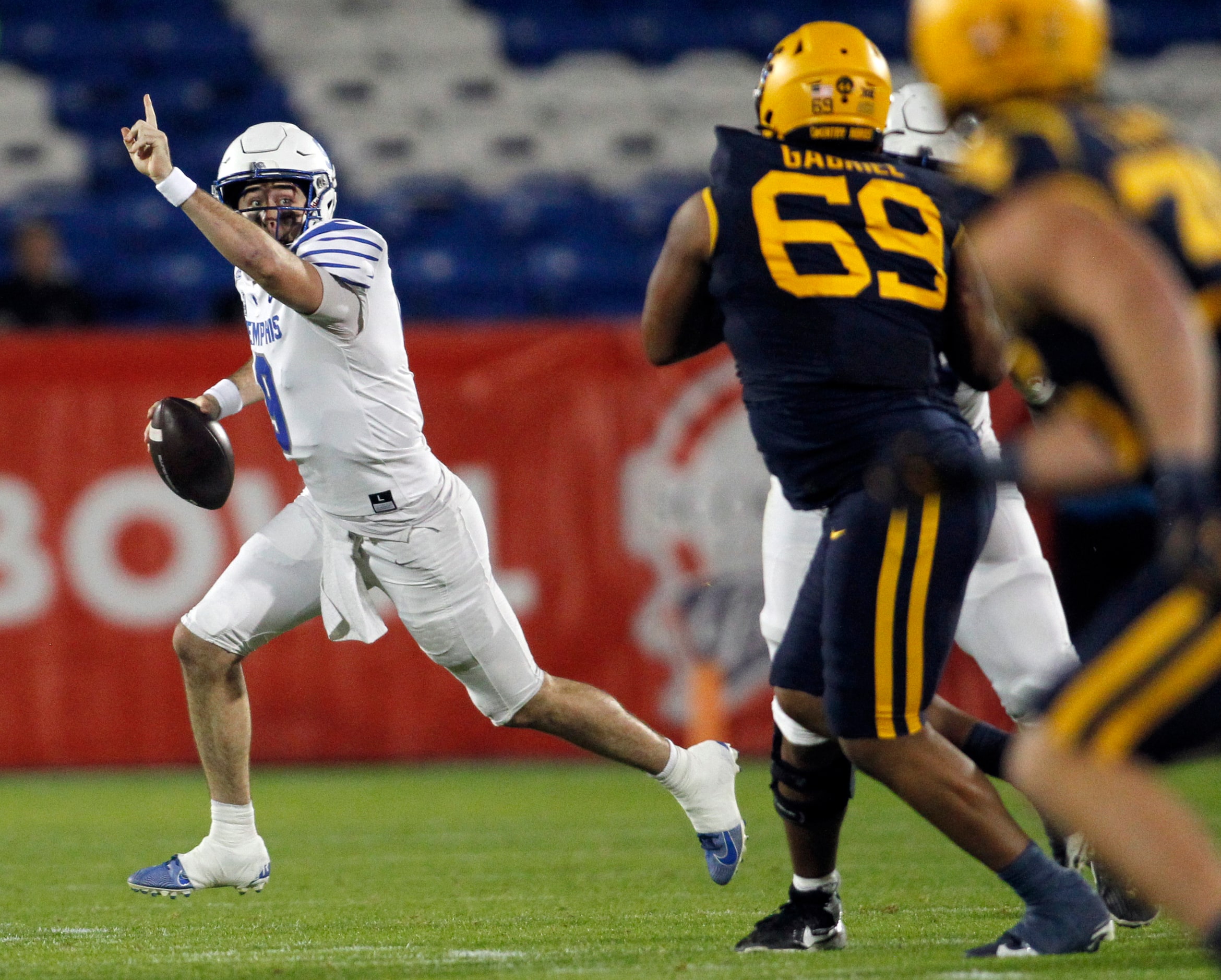 Memphis quarterback Seth Henigan (9), left, rolls out and directs his receiver to head...