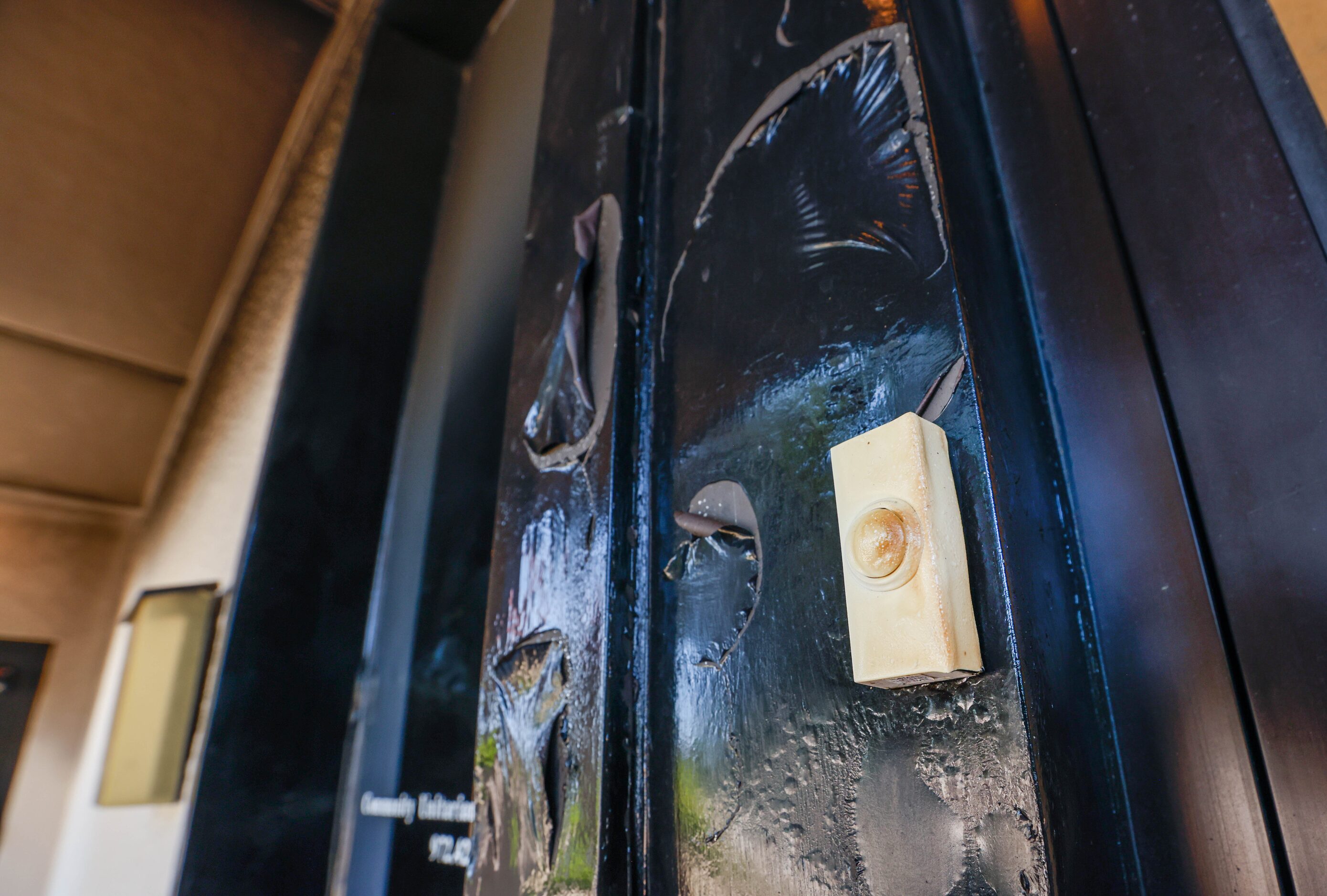 A doorbell is warped and darkened on the doorway of Community Unitarian Universalist Church...