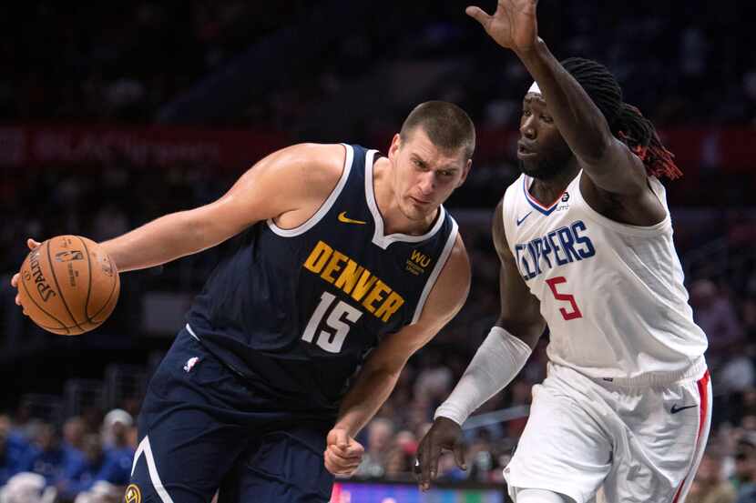 Denver Nuggets center Nikola Jokic, left, drives toward the basket as Los Angeles Clippers...