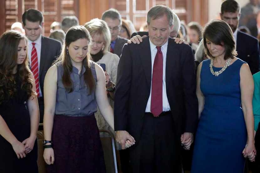 
Ken Paxton, center, joins hands with family members during a prayer after he was sworn in...