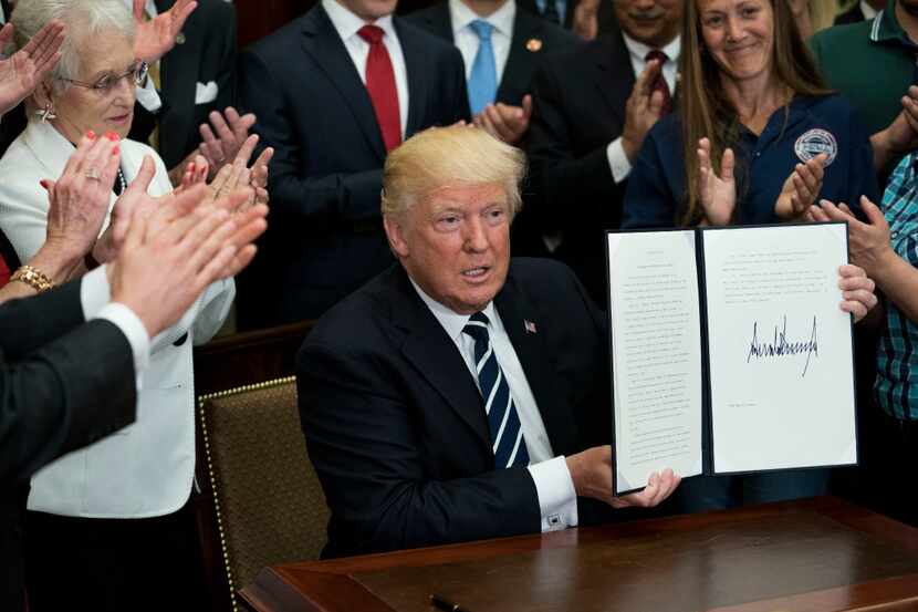 President Donald Trump holds up an executive order he signed for the "Apprenticeship and...