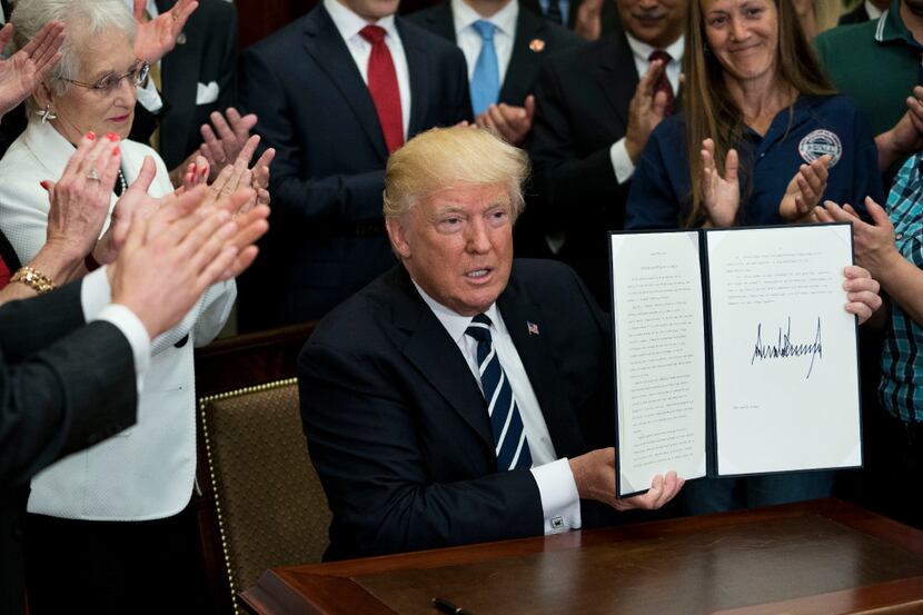President Donald Trump holds up an executive order he signed for the Apprenticeship and...