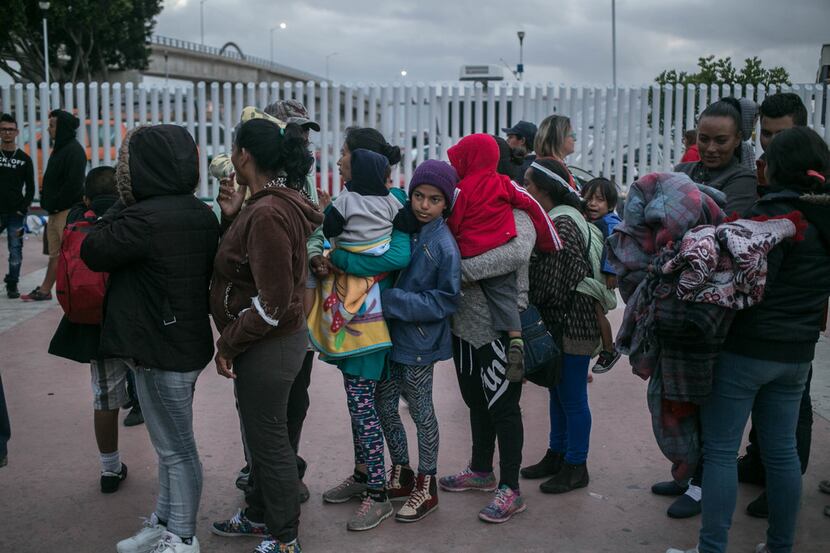 A caravan of migrants from Central America who traveled through Mexico lineup outside...