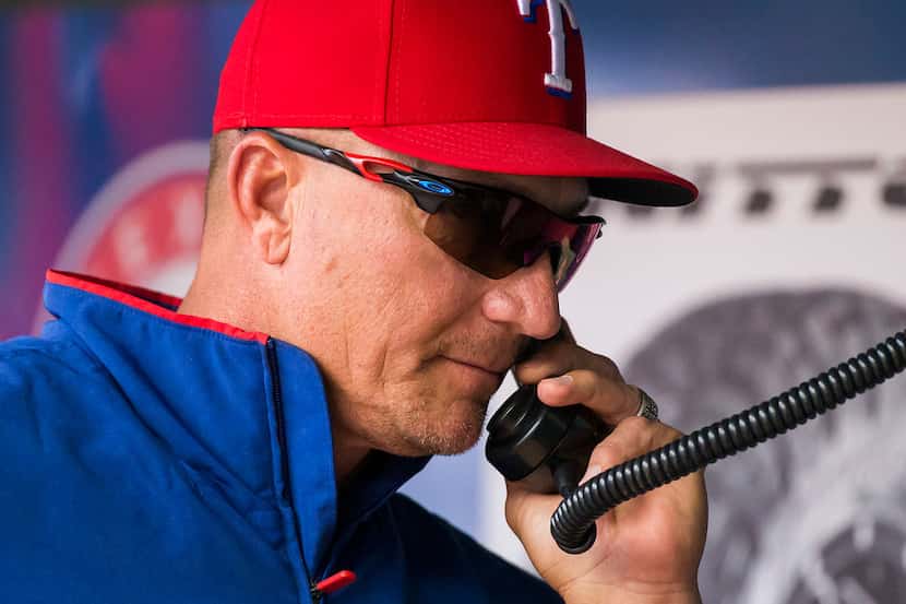 Texas Rangers manager Jeff Banister makes a call to the bullpen before replacing relief...