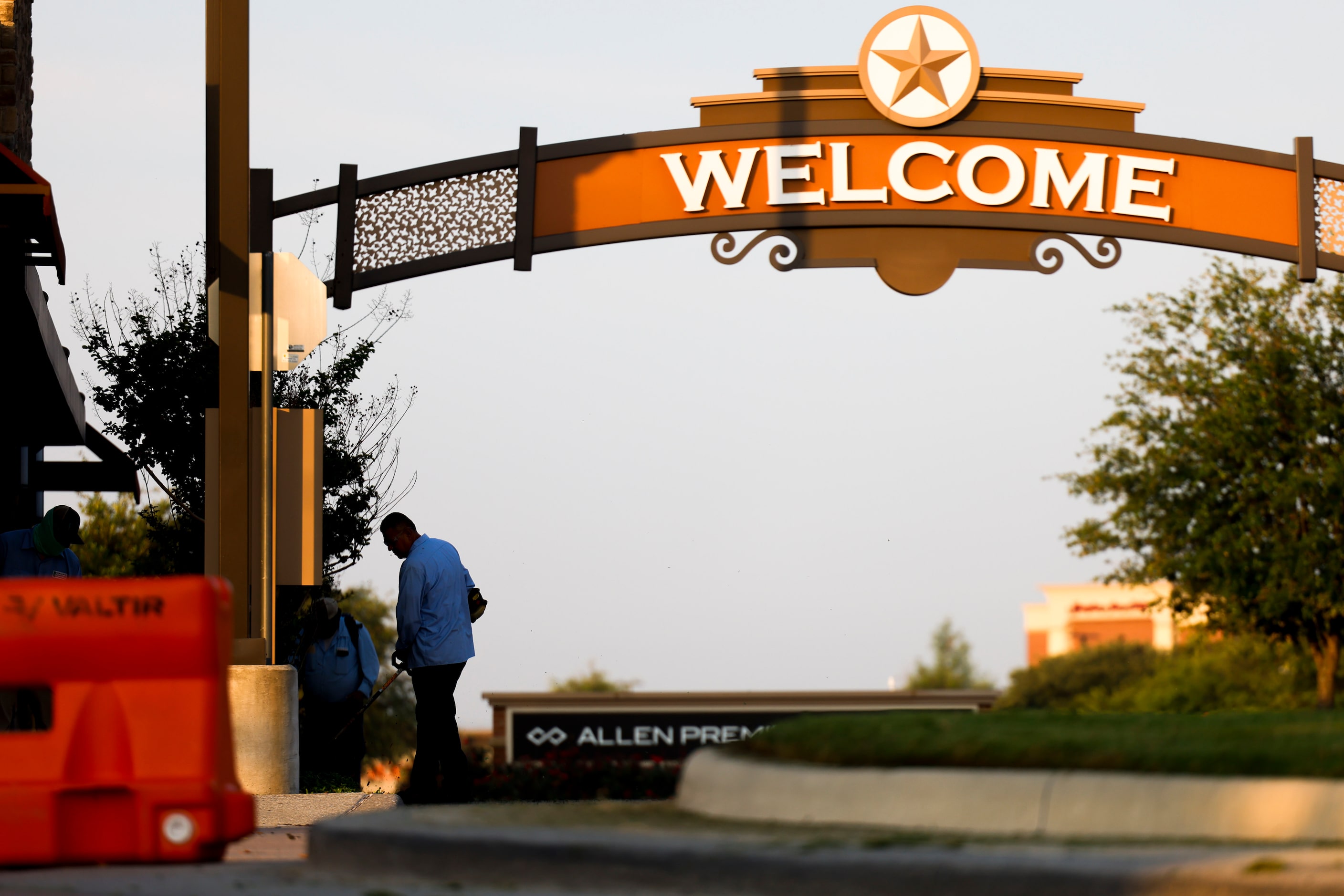 Landscape workers work outside of the north entrance of Allen Premium Outlets mall on the...