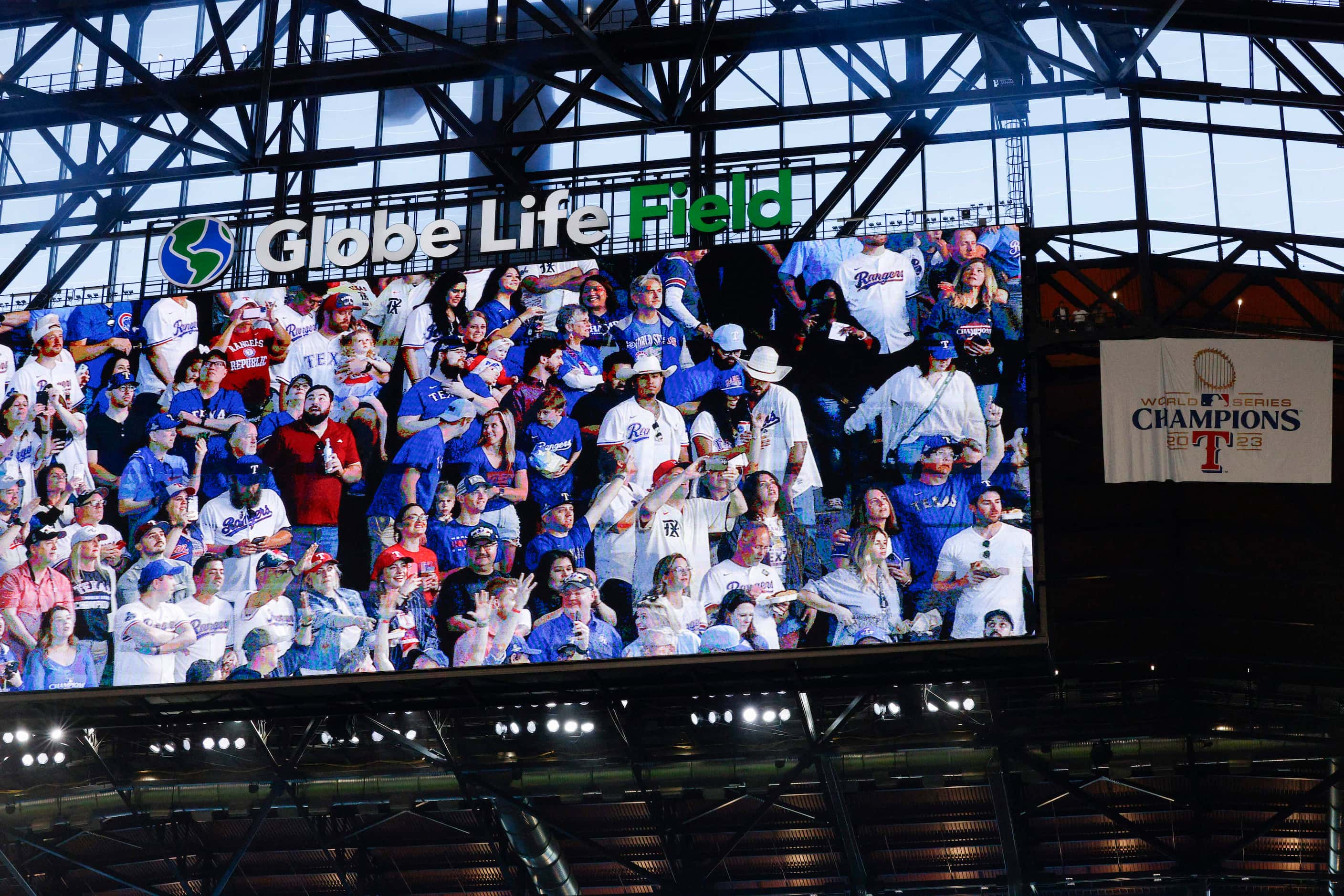 Fans are shown on the video board after the Texas Rangers World Series champions banner was...