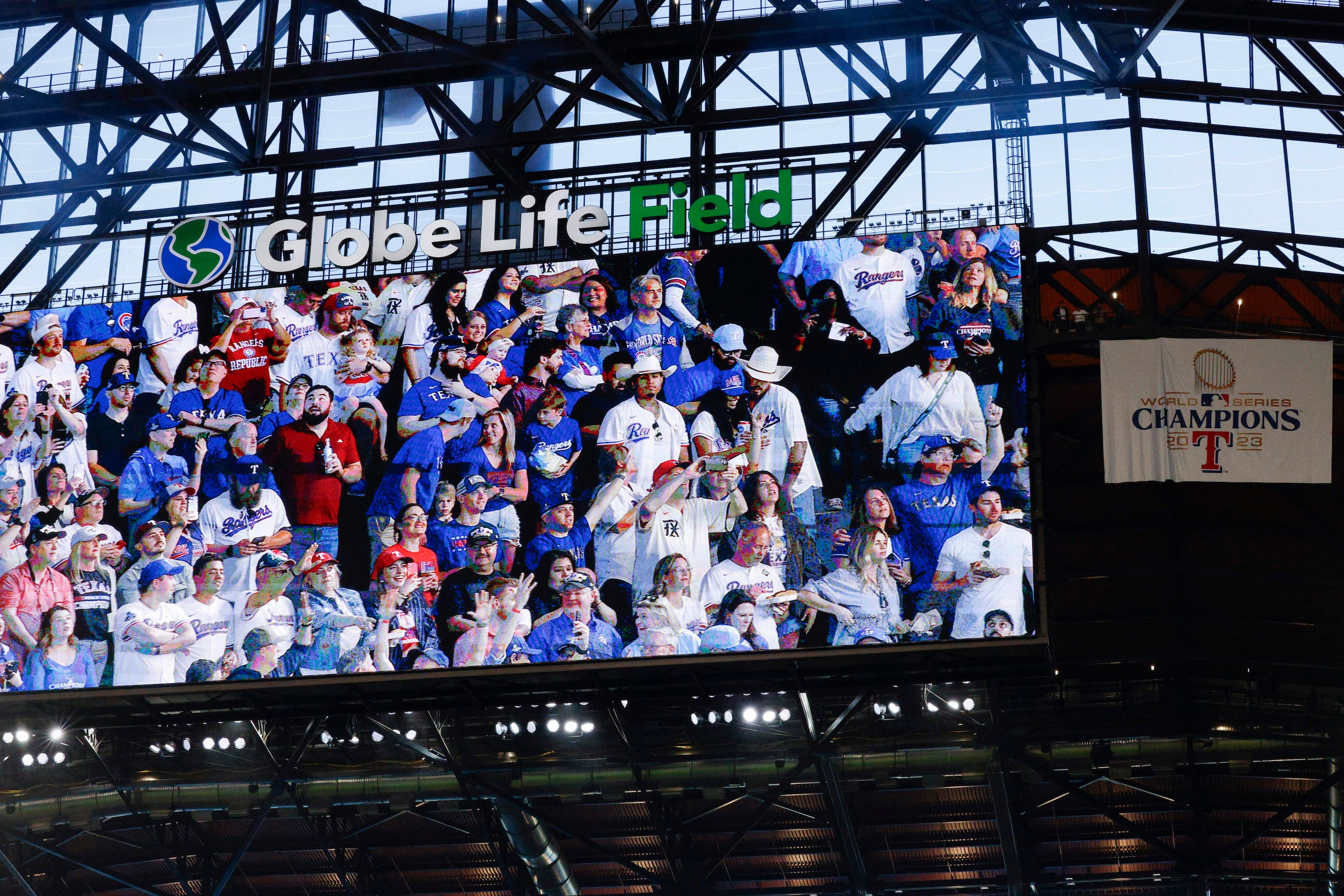 Fans are shown on the video board after the Texas Rangers World Series champions banner was...