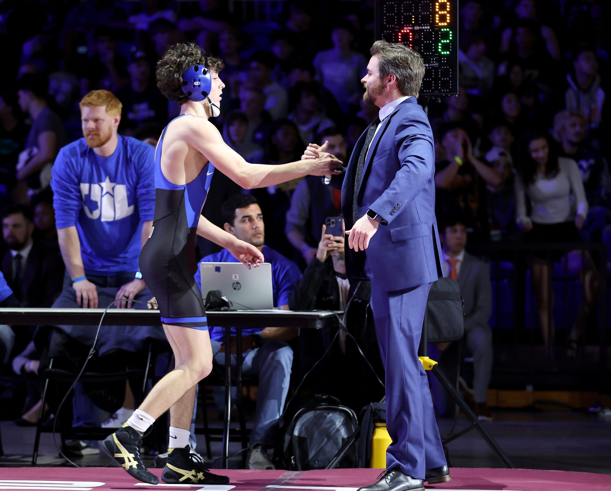 Eli Biermann of Midlothian (blue) celebrates with his coach after defeating Nathaniel Ruiz...