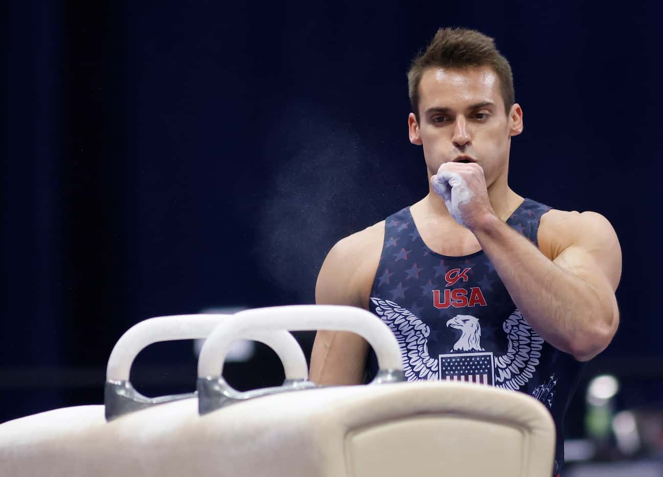 Sam Mikulak blows chalk off his hand before competing on the pommel horse during day 2 of...