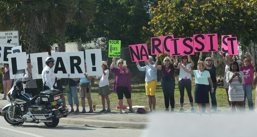 Protesters demonstrate as the Trump motorcade passes by enroute Palm Beach International...